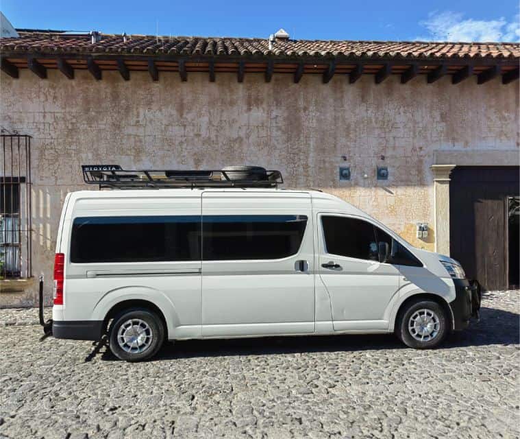 An Antigua Panajachel shuttle sprinter van in front of a painted colonial-style building in Antigua Guatemala.