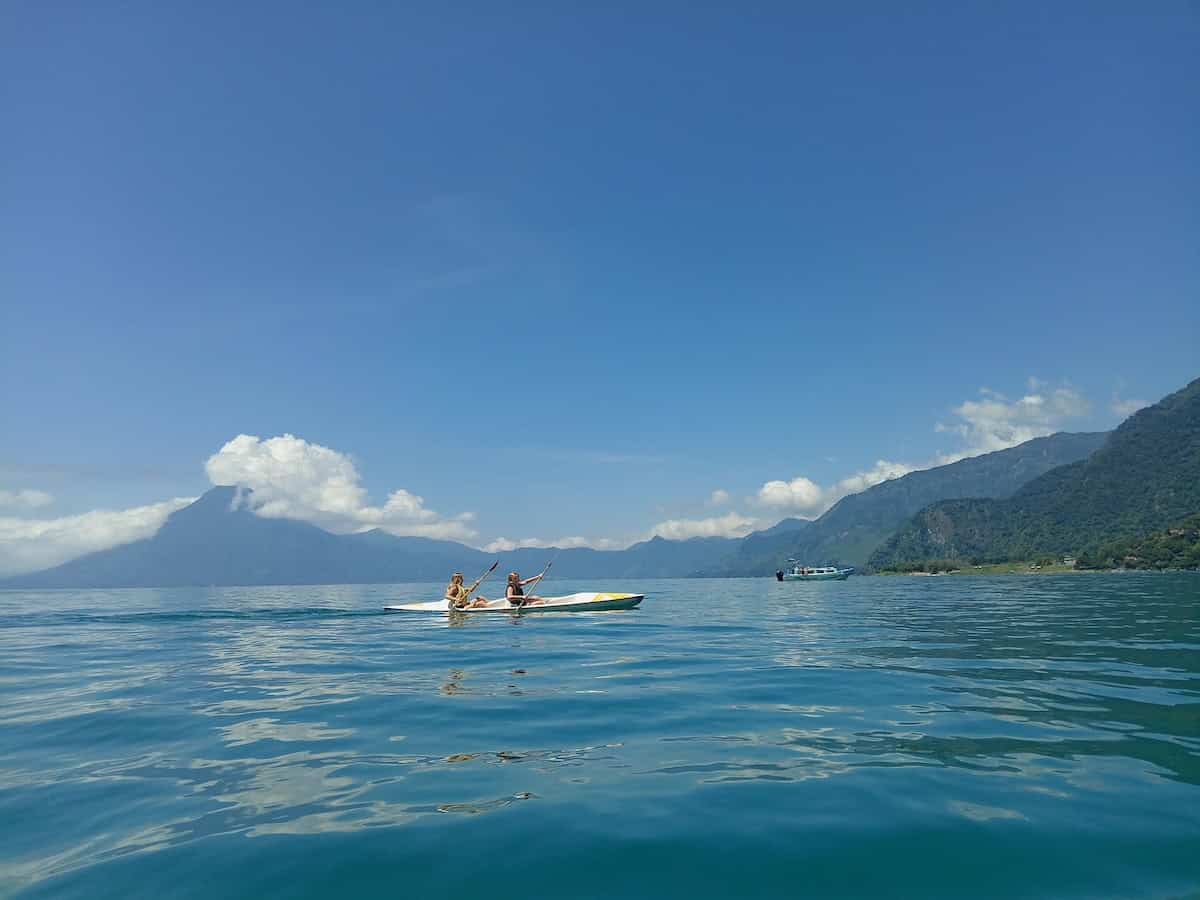 Two girls kayak on Lake Atitlán with volcanoes in the background.