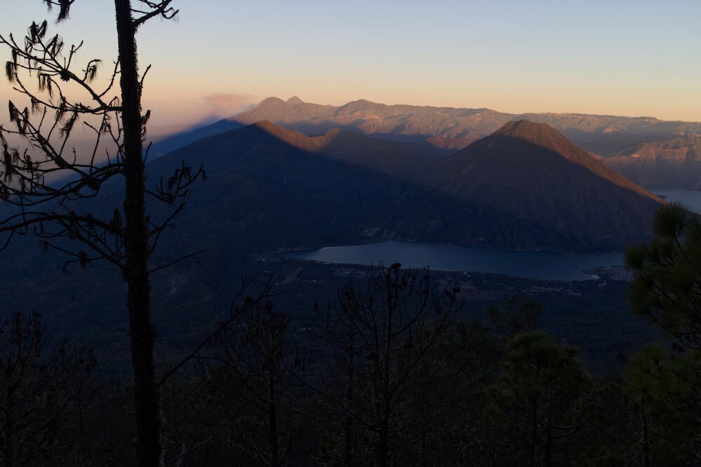 Two triangular volcanic shadows stretch across a volcanic landscape painted in the golden hues of dawn.